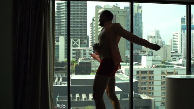 Happy man in underwear dancing by window at home, super slow motion