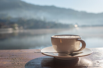 Hot coffee latte with beautiful view in morning sunrise light.