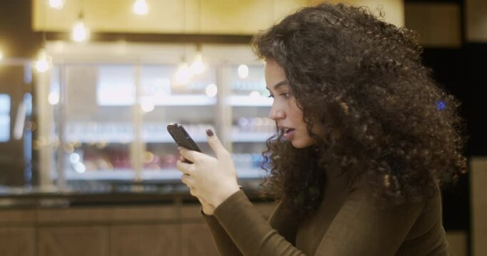 Attractive lovely Brazilian woman cheerful cheery wavy-haired lady using 5g. Latin America girl surprised holding a smartphone. 4K.