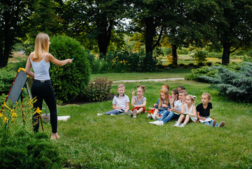 A teacher teaches a class of children in an outdoor Park. Back to school, learning during the pandemic