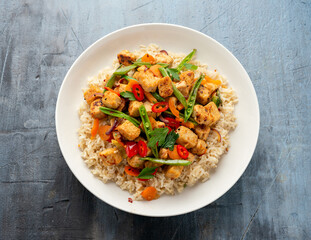 Vegetarian meat free mycoprotein pieces vegetable stir fry, brown rice served in white plate