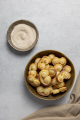Puff pastry eyelet, Palmier cookies in a bowl with cinnamon and sugar on the light concrete background. Top view. 