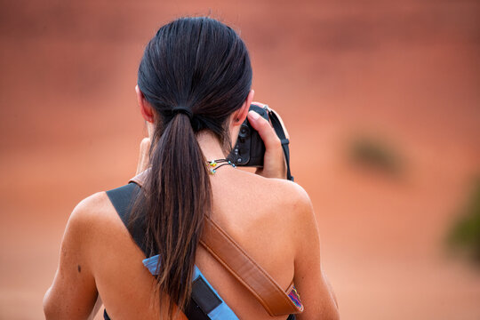 Back view of a caucasian female tourist photographing a National Park landscape