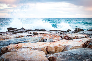 rocks on the beach, waves crushing in at sunset