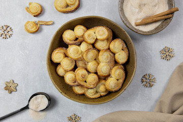 Puff pastry eyelet, Palmier cookies in a bowl with cinnamon and sugar on the light concrete background. Top view. 