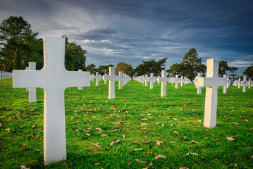 Under a moody sky, crosses mark the final resting place of soldiers in the military cemetery Colleville-sur-Mer, Omaha Beach, Normandy.