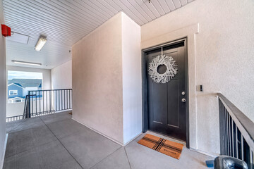 Apartment unit with white wreath dark gray door and doormat at the entrance