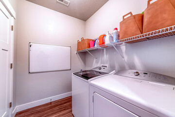 Laundry room with washing machine and dryer under detergents and soaps on rack