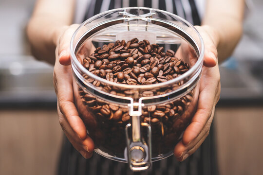 Shopkeeper woman Hold a glass jar of roasted coffee beans. Concept of entrepreneurship, SME business