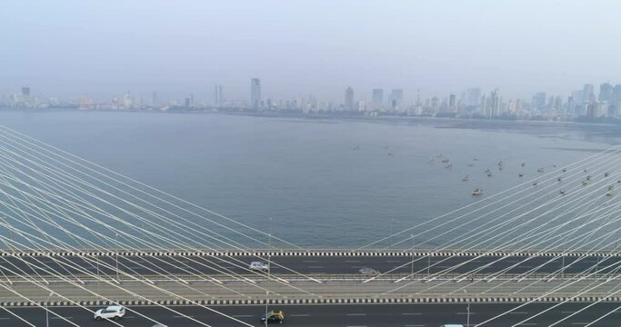 Flying over the iconic Bandra Worli Sea link bridge in Mumbai revealing the city view in the back.