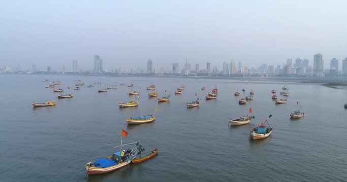 Flying sideways with Koliwada Fishermen's boats parked in foreground while the Mumbai City view in the back under a smog like hazy weather.