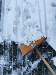 Wintereinbruch, Winter, Winterdienst, Schnee schieben mit einem Schneeschieber aus Holz, Sicherheit auf Gehwegen gewährleisten, Sturzgefahr vermindern