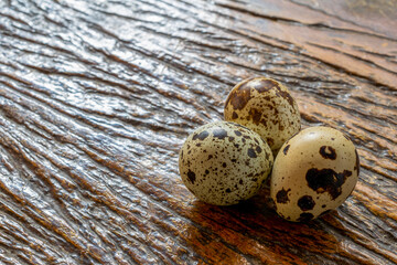 three quail eggs on rustic wooden table