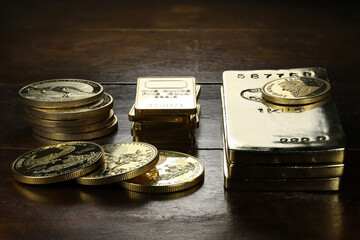 gold ingots an various bullion coins on wooden background