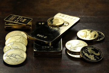 gold ingots an various bullion coins on wooden background