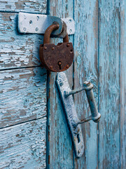 Locked old red double door with rusty padlock. Peeled door