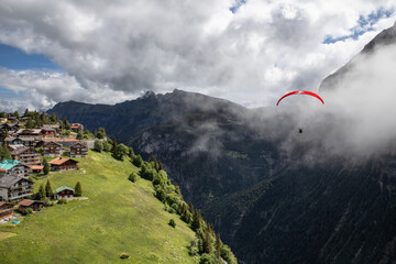 Parasailor glides over lush valley and lofty clouds
