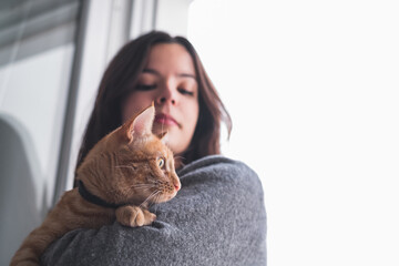 Pretty woman holding and looking at a cat
