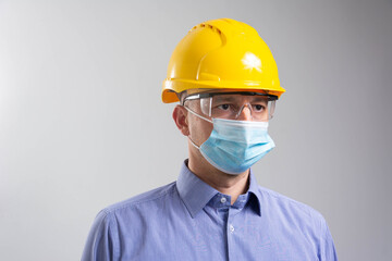 Young engineer worker wear a yellow helmet and medical mask. Coronavirus Hygiene, safety concept