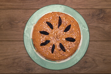 Homemade honey cake with cream, nuts and prunes on a wooden table. Top view