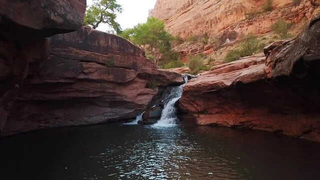 Drone video in a red canyon with a waterfall in Moab, Utah