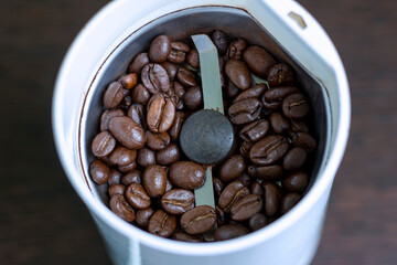 Roasted arabica coffee beans in an electric coffee grinder.