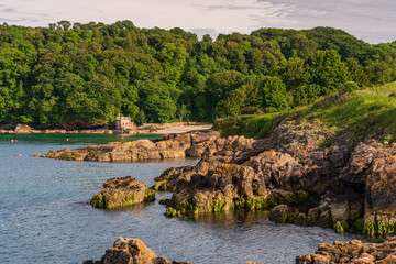 Walking towards Elberry Cove, Torbay, England, UK - with the disused bath-house on the edge of the...