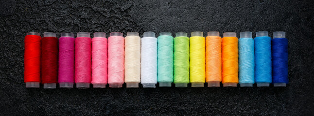 Sewing threads in row multicolored background closeup