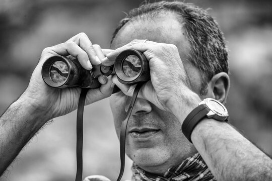 Male tourist using binoculars while examining area