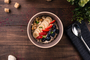 Oatmeal porridge in bowl topped with blueberries, bananas and strawberries. Healthy breakfast oatmeal porridge with fresh fruits and berries
