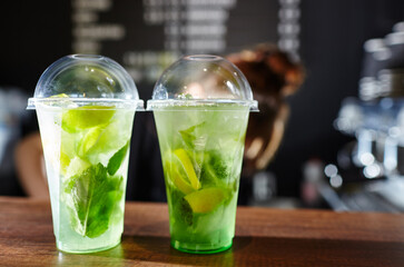 Bartender making mojito cocktail. Process of bartending in bar. Fresh cocktail drink with ice fruit and herb decoration