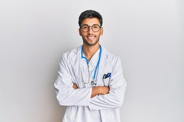 Young handsome man wearing doctor uniform and stethoscope happy face smiling with crossed arms...