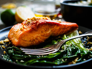 Fried salmon steak with lemon, basmati rice and steamed pak choi cabbage served on wooden table
