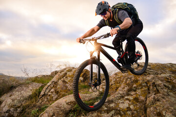 Professional Cyclist Riding Bike on the Autumn Rocky Trail at Sunset. Extreme Sport and Enduro...