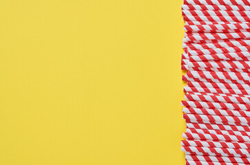 Fototapeta premium Drinking tubes made of red and brown paper and cornstarch, biodegradable material on yellow trend color 2021 background. Zero waste concept. Top view.