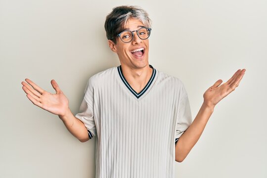 Young hispanic man wearing casual clothes and glasses celebrating crazy and amazed for success with arms raised and open eyes screaming excited. winner concept