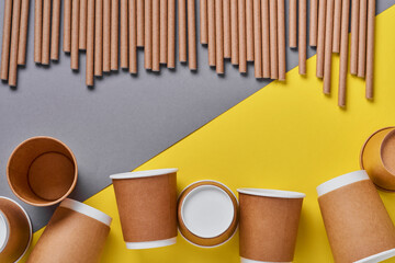 Drinking tubes made of paper and cornstarch, biodegradable material and eco paper glasses on yellow...