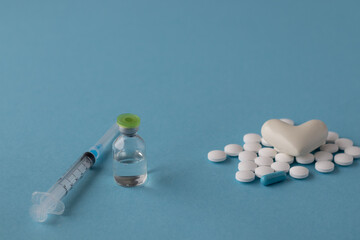The white heart on pills with masks and syringes on a blue background. 