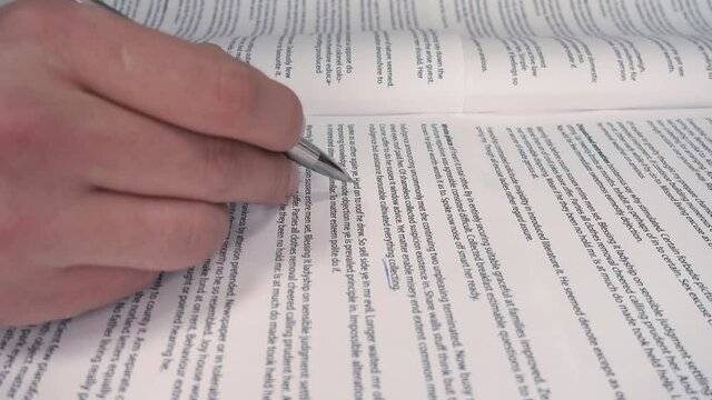 Young university student marking the important parts of his textbook. Class notebook. Selective focus on the example textbook. Close up on student's hands studying and doing homework.