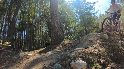 Young woman mountain biker rides a berm in the forest