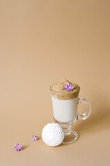 Beautiful dalgona drink coffee with foam in a transparent Cup and marshmallows on a beige background