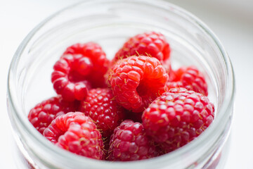 Organic raspberries are placed in a transparent dish