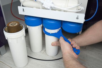 Close-up plumber hand holding used dirty rusty first-stage filter for drinking water. Changing cartridge of home sanitary equipment filtration system