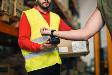 Closeup of modern man paying via smartwatch while buying package in warehouse - Industrial worker