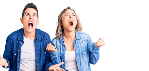 Couple of women wearing casual clothes crazy and mad shouting and yelling with aggressive expression and arms raised. frustration concept.