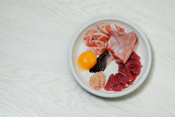 Natural cat food. Raw salmon fish, meat, egg in bowl on white background. Healthy food for cats.