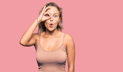 Fototapeta premium Beautiful caucasian woman wearing casual clothes doing ok gesture shocked with surprised face, eye looking through fingers. unbelieving expression.