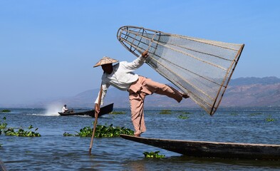 A fisherman of Inle lake, in Myanmar, using the traditional Wooden boat and net.