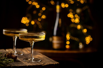 Two Glasses of champagne and bottle against fireworks and holiday lights, dark background