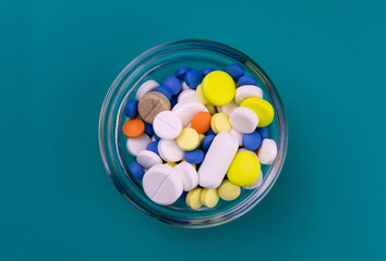 
Lots of pharmaceutical pills in a stellan bowl on a blue background. View from above.